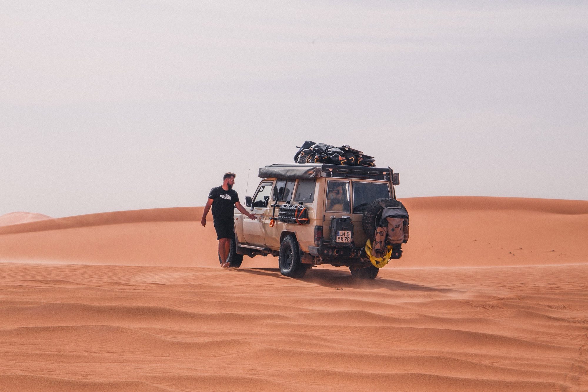 Lukas Reusch neben seinem Geländewagen in den Dünen der Sahara